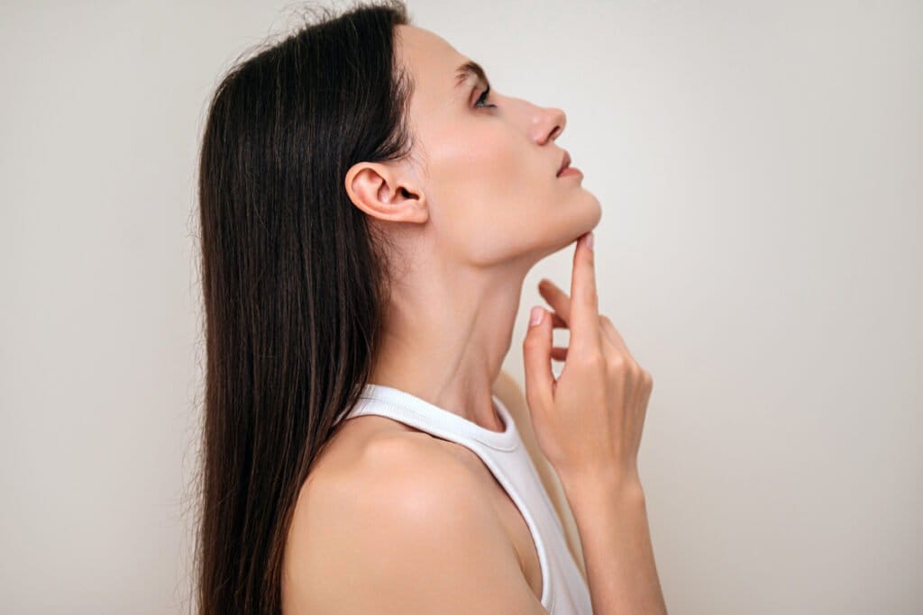 Profile view of woman touching her chin with a contoured jawline