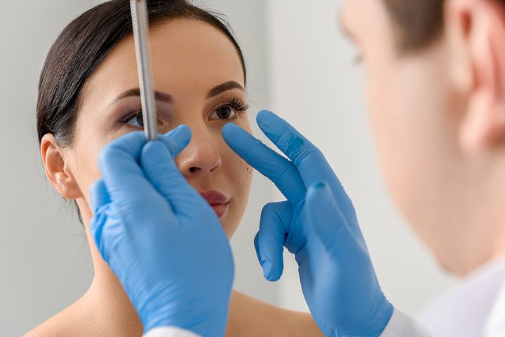 Plastic surgeon examining patient's nose for nose surgery