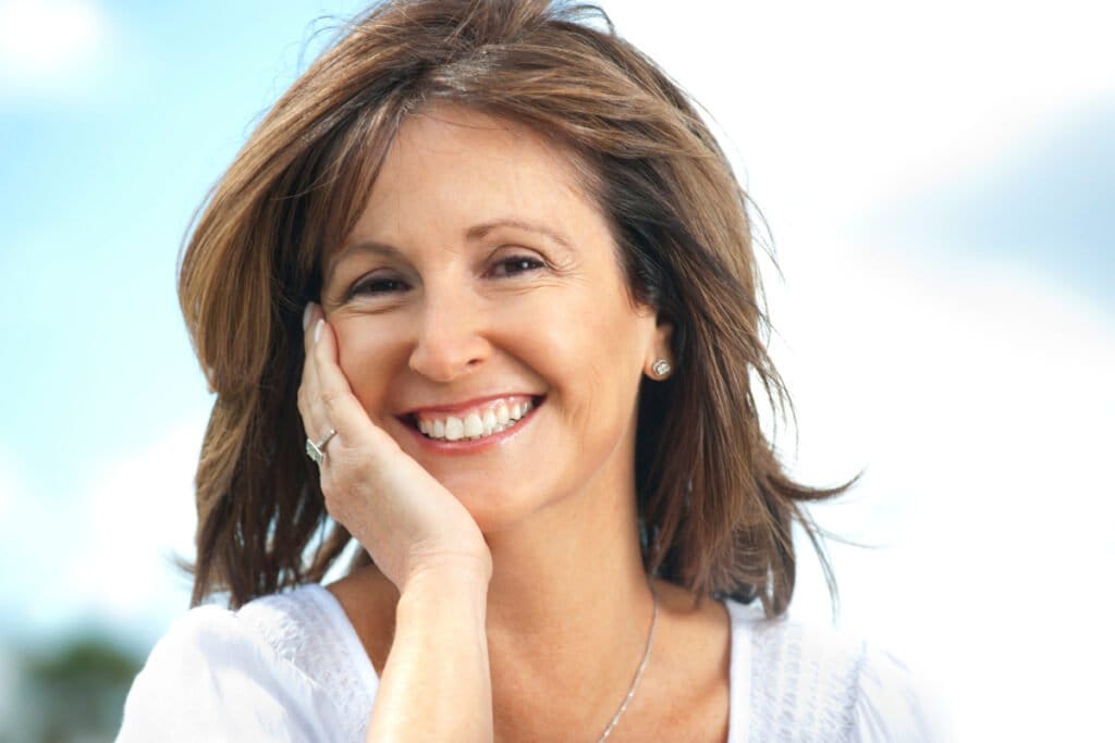 Mature woman smiling and touching face