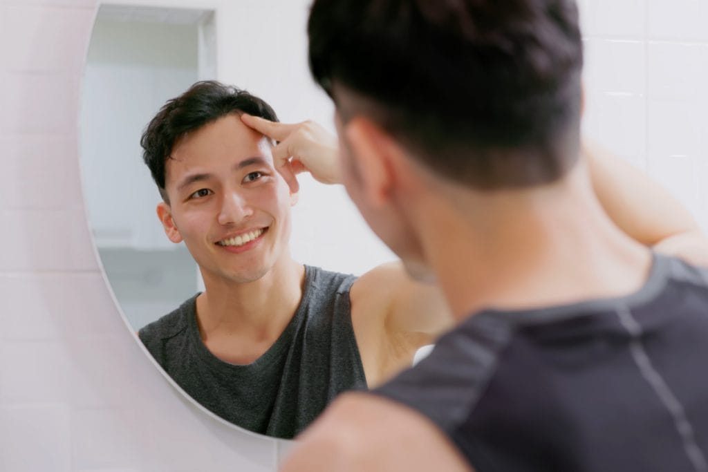 Man looking at hairline in mirror